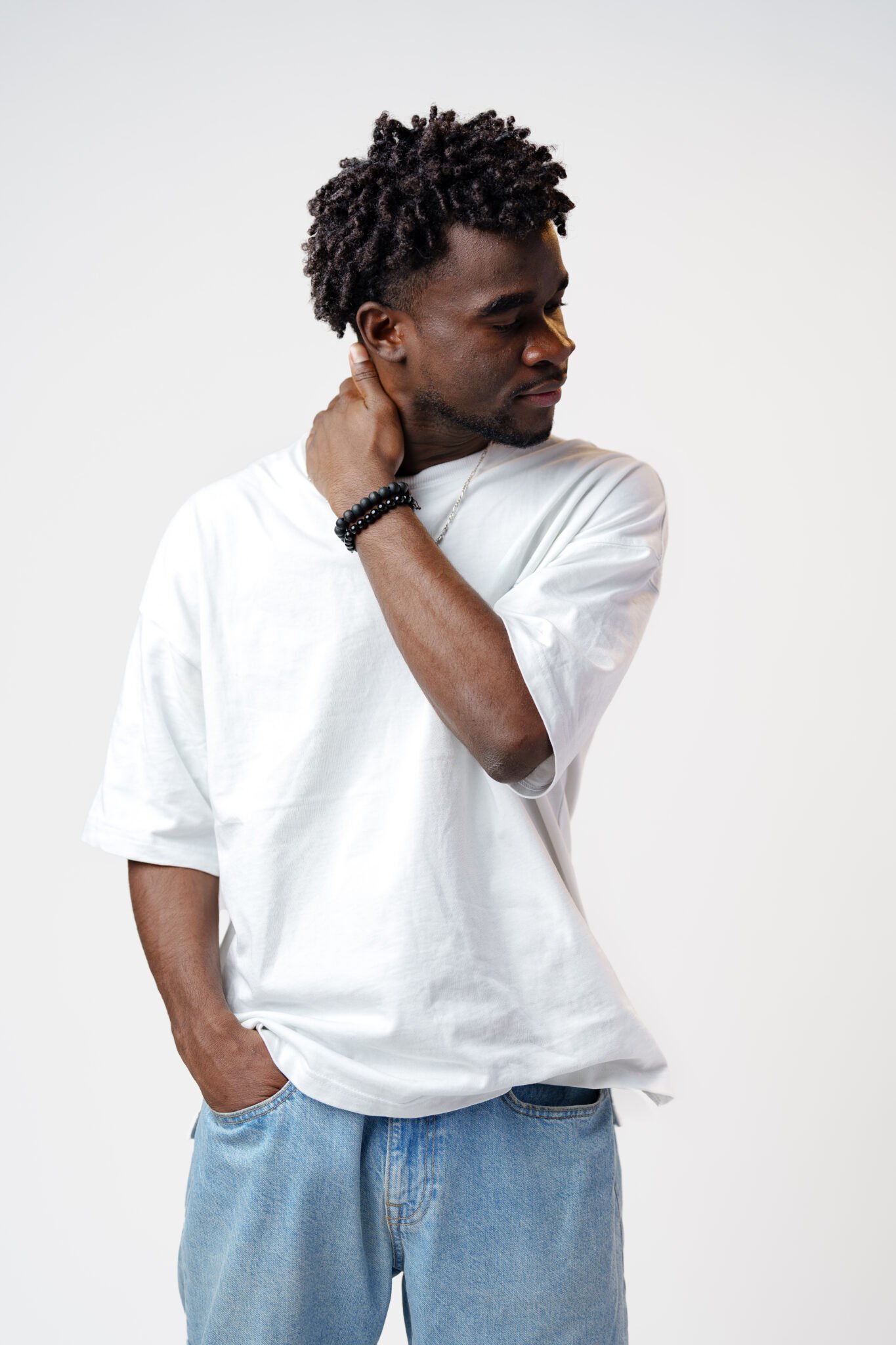 Portrait of a smiling young african man wearing white t-shirt standing over gray background in studio